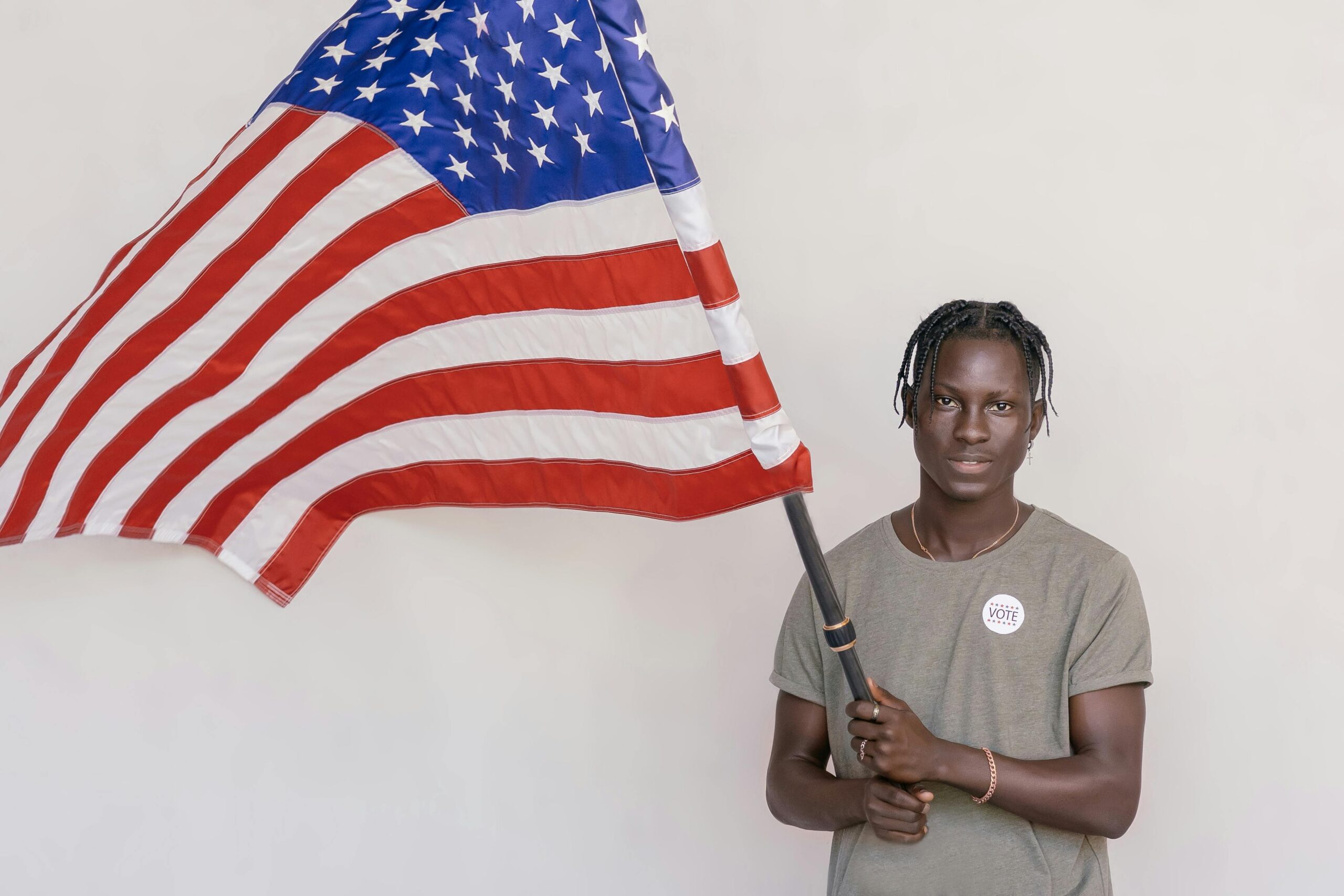 A young man proudly holding the US flag in a studio. Promotes patriotism and civic engagement.